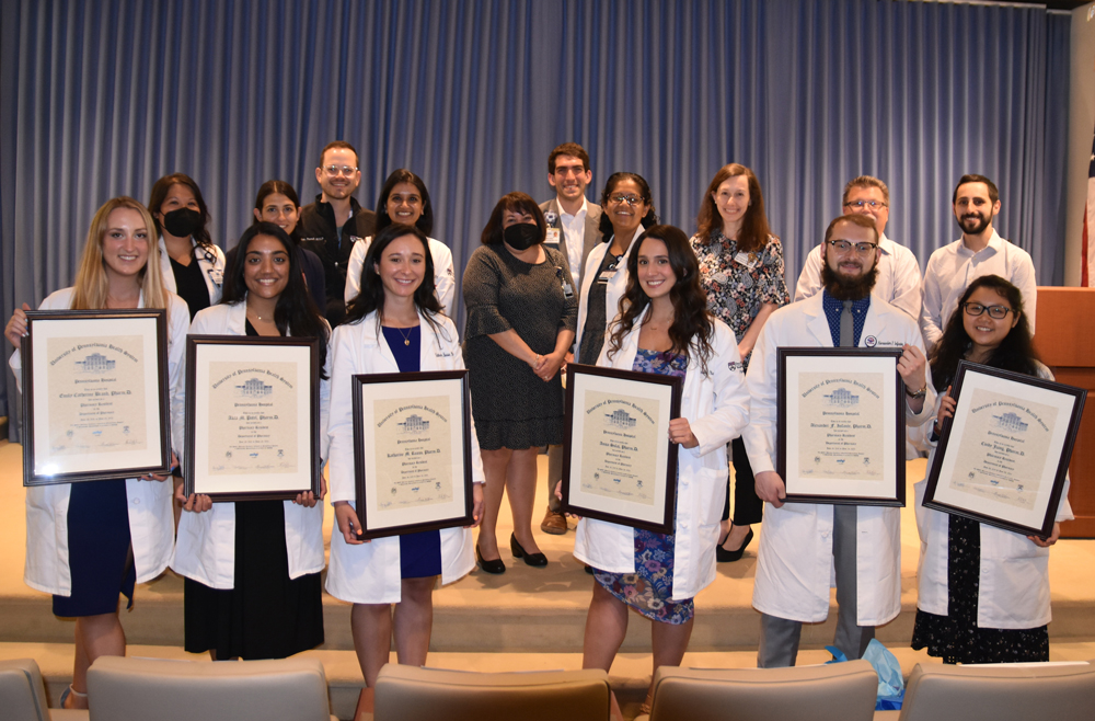 Faculty and residents holding framed certificates in the Zubrow auditorium
